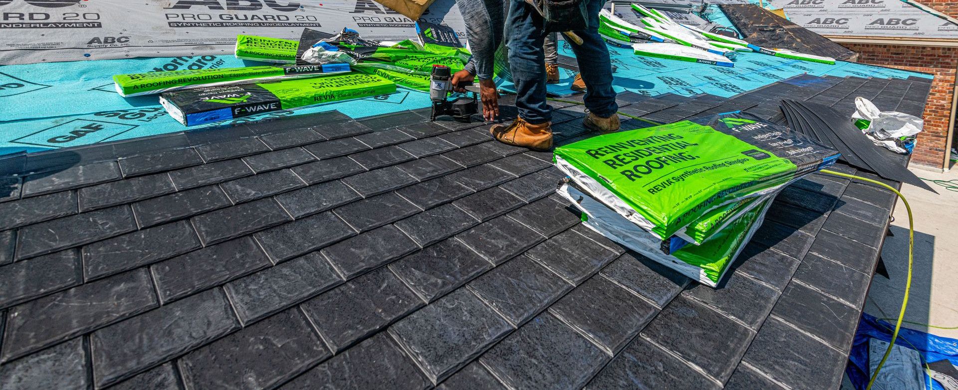 Workers installing a synthetic slate roof on a brick house in Fort Worth, Texas.