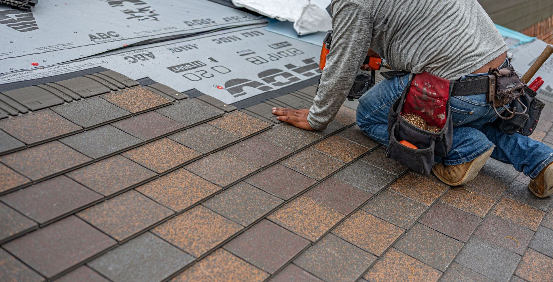 Skilled roofer installing asphalt shingles, ensuring quality home renovation.