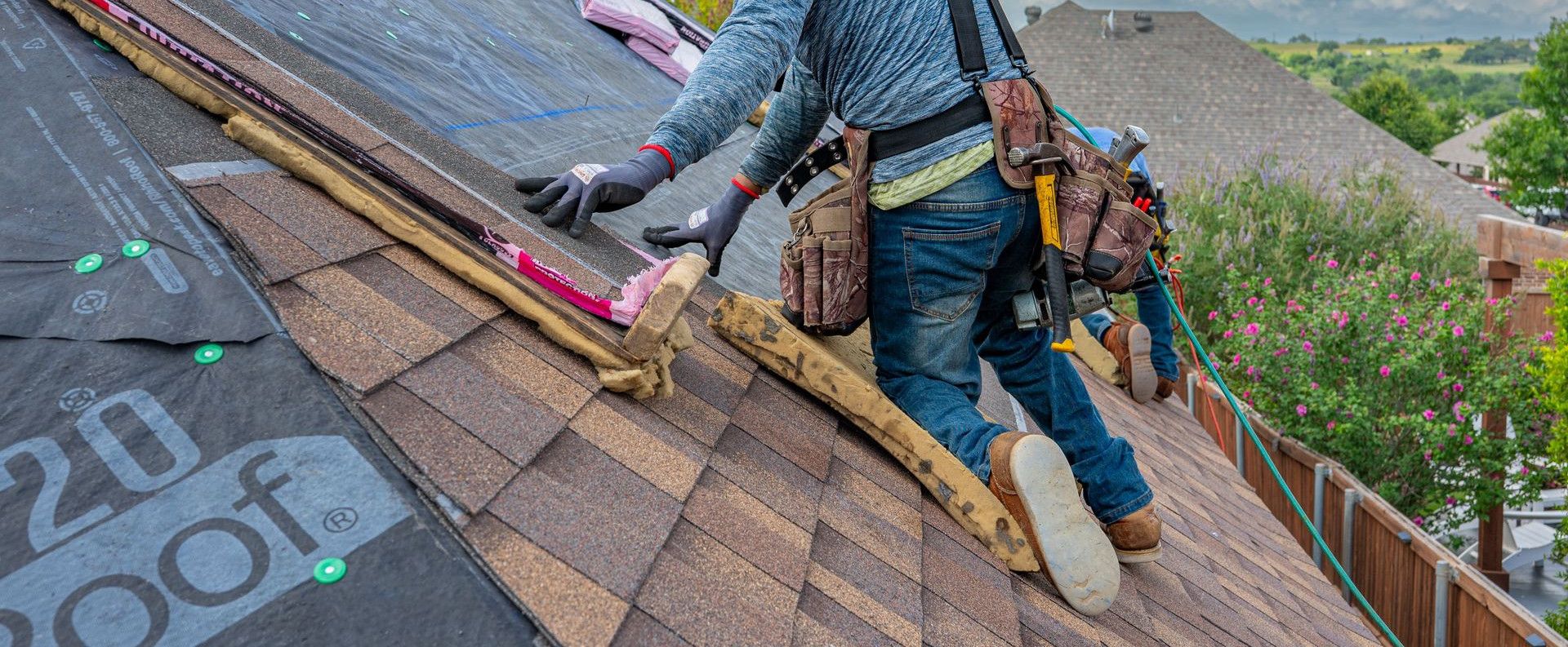 Roofers working on shingle installation on a home in Fort Worth, Texas under blue skies.